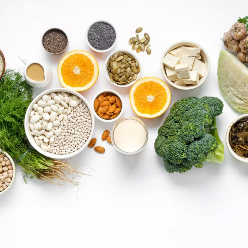 פריסה של מאכלים מן הצומח שעשירים בסידן על רקע לבן